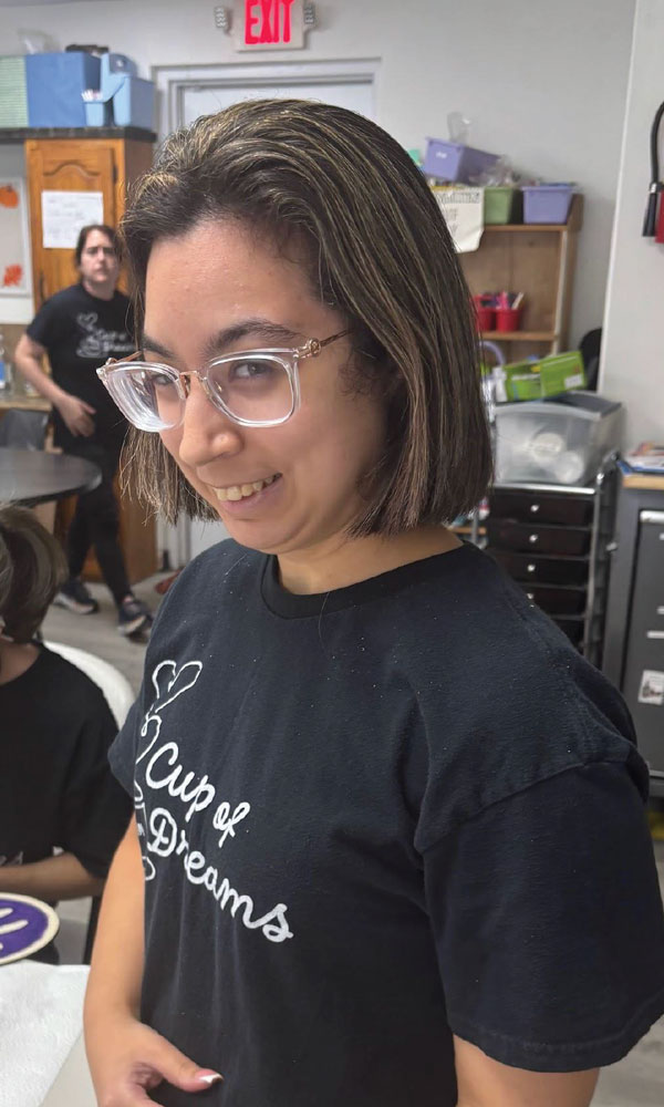 Starr smiling in glasses and a black Cup of Dreams T-shirt.
